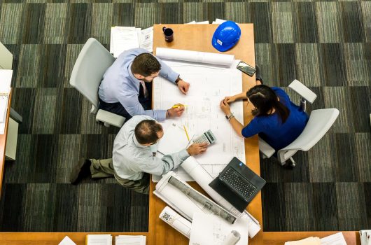 Photo of 3 people looking at some plans at a desk.